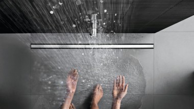 Person showering in a floor-even shower with CleanLine