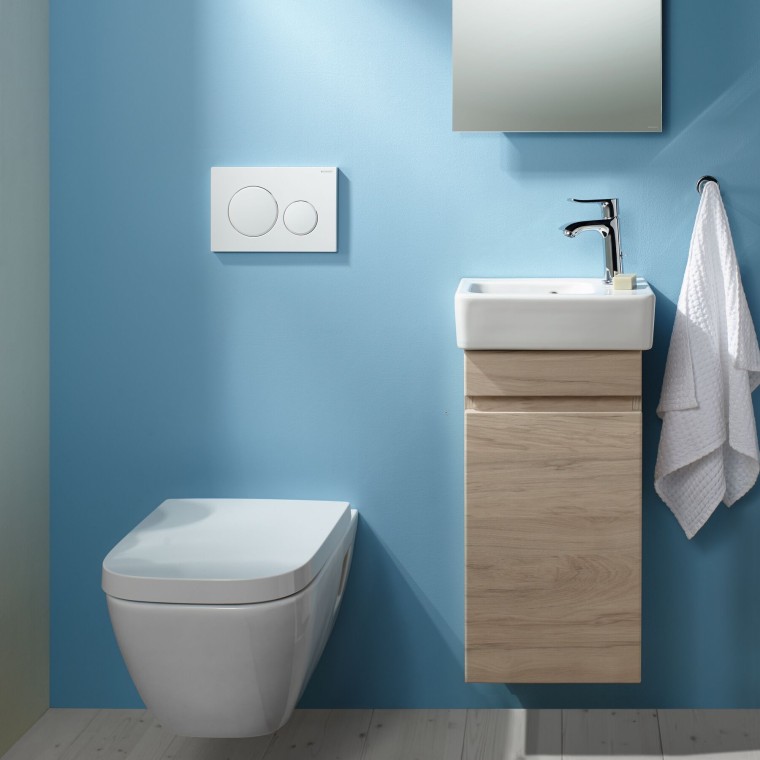 A wall-hung Renova Plan WC and a washbasin area attached to a light blue wall A wall-hung Renova Plan WC and a washbasin area attached to a light blue wall