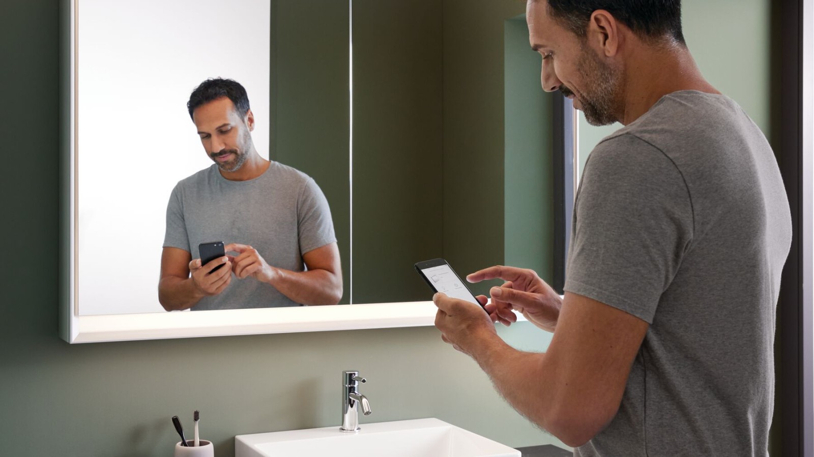 Man standing in the bathroom with a mobile phone Man standing in the bathroom with a mobile phone