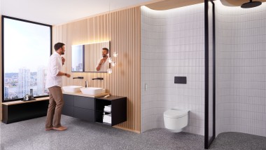 Man in bathroom standing in front of Geberit Option Plus Square mirror and black Geberit ONE bathroom furniture (© Geberit)