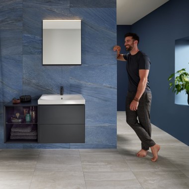 Man leaning against wall in blue bathroom with Geberit Mix & Match washplace