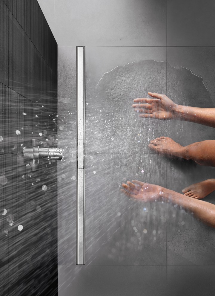 Person showering in a floor-level shower equipped with the Geberit CleanLine shower channel