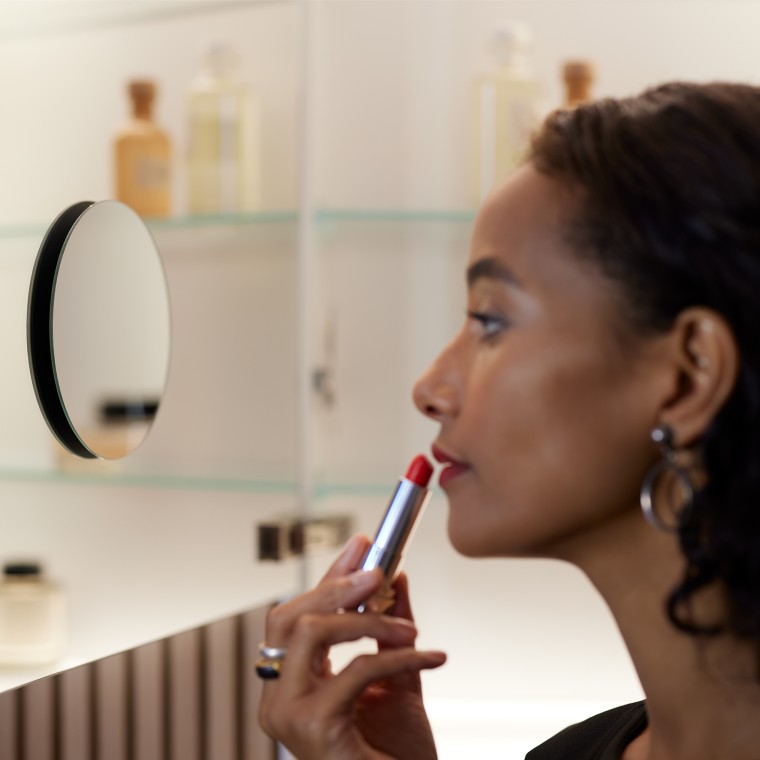 Woman applying make-up in the mirror
