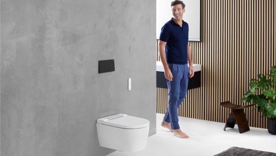 Man in the bathroom looking at the WC area featuring a Geberit toilet Man in the bathroom looking at the WC area featuring a Geberit toilet