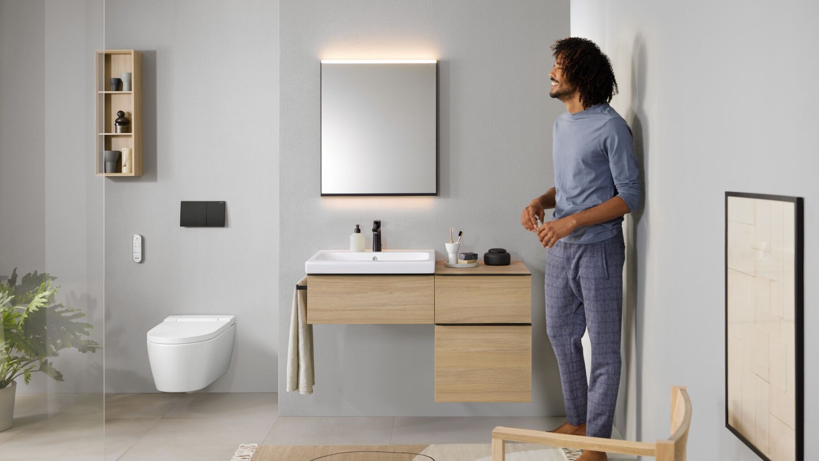 Man standing in a bathroom with an AquaClean Sela shower toilet. Toilets with bidet function look just like a normal toilet but have a range of comfort functions. Man standing in a bathroom with an AquaClean Sela shower toilet. Toilets with bidet function look just like a normal toilet but have a range of comfort functions.