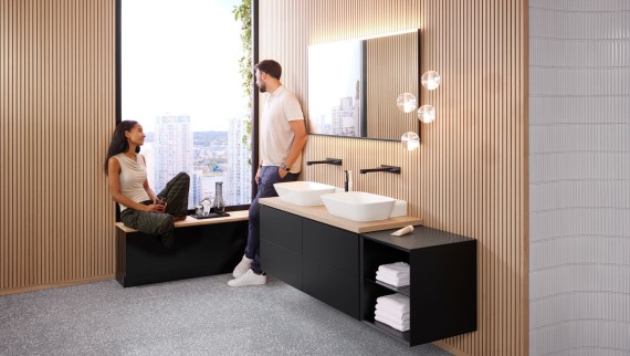 A woman and a man in a large bathroom with Geberit ONE double washbasin, Option mirror and wood elements A woman and a man in a large bathroom with Geberit ONE double washbasin, Option mirror and wood elements