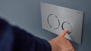 Hand actuates small flush at the Sigma40 Round actuator plate (© Geberit)