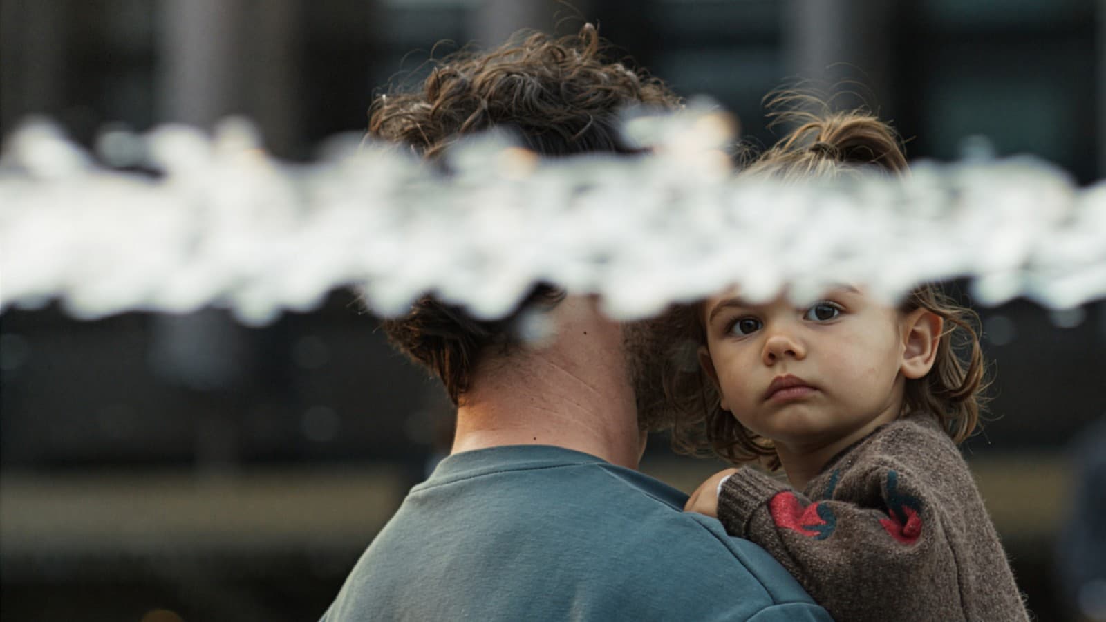 A girl in her father’s arms, with a jet of water in the foreground A girl in her father’s arms, with a jet of water in the foreground